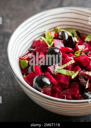 Bowl with a home made beet salad with minted beets, olives and fresh mint leaves. Stock Photo