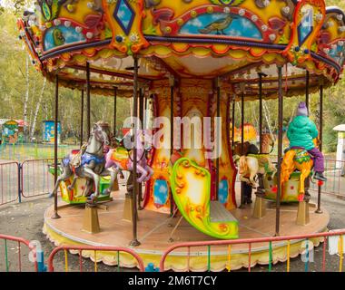 Children ride on the horses on the colorful carousel in the Park Stock Photo