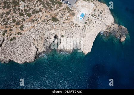 Drone aerial photograph of Cape Greco peninsula with Agioi Anargyroi church on the rocks. Turquoise ocean water Stock Photo