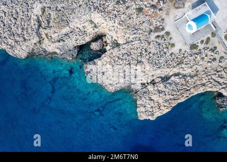 Drone aerial photograph of Cape Greco peninsula with Agioi Anargyroi church on the rocks. Turquoise ocean water Stock Photo