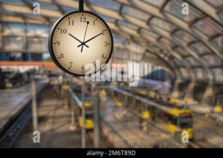 Old fashioned station clock on blurry train station background. Illustration of the concept of time, schedule and travel Stock Photo