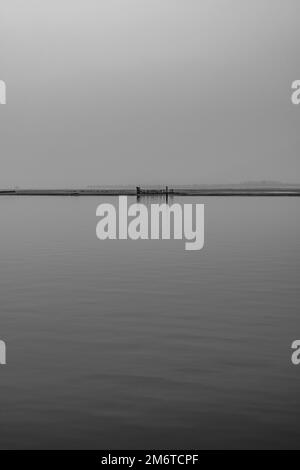 Grado, Italy - January 01th 2023:  View of the ancient Roman wrecks on the lagoon. Foggy day in winter. Vertical shot. Stock Photo