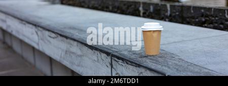 banner or used disposable paper cup abandoned on concrete bench in city street Stock Photo