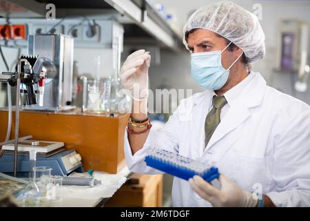 Male chemist working in laboratory, analyzing liquid samples in flasks Stock Photo