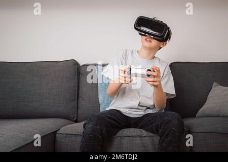 Boy having fun playing simulation games, using virtual reality headset and controller. Children and modern technology concept. Stock Photo