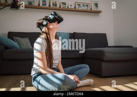 Young woman using virtual reality equipment, VR glasses, to look around the artificial world Stock Photo
