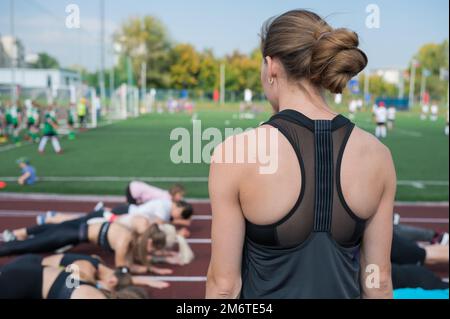 Female coach and group of children conducts a training session Stock Photo