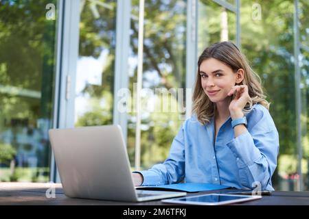 Portrait of business woman working on fresh air. Corporate female with laptop, sitting outside office building and using compute Stock Photo
