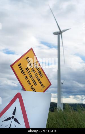 Wind Turbines with a caution sign warning of the dangers of approaching the turbine Stock Photo