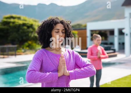 Diverse friends practicing yoga and meditating in garden Stock Photo