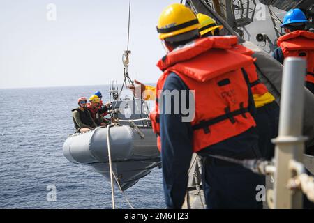 Sailors hoist a small boat aboard the guided-missile destroyer USS ...