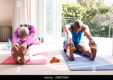 Happy senior diverse couple practicing yoga and stretching Stock Photo