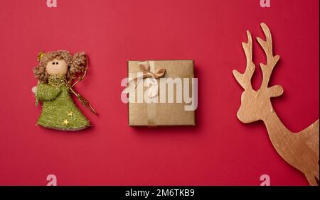 Golden wooden deer toy, a gift on a red background, top view. Stock Photo