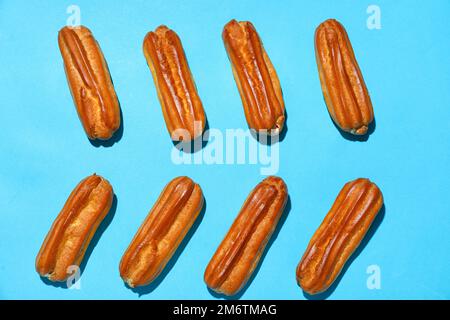 Composition with sweet eclairs on blue background Stock Photo