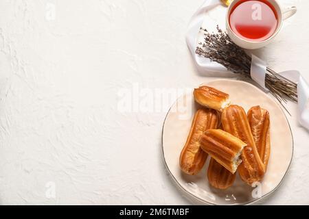 Composition with cup of tea, tasty eclairs and lavender on light background Stock Photo