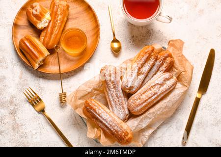 Composition with sweet eclairs and honey on light background Stock Photo
