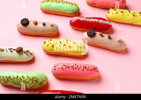 Many delicious glazed eclairs on pink background Stock Photo