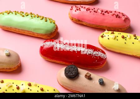 Many delicious glazed eclairs on pink background Stock Photo