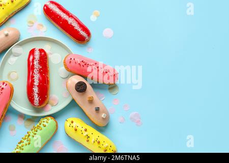 Plate and various glazed eclairs on blue background Stock Photo