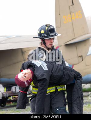 A firefighter from the 788th Civil Engineer Squadron carries a dummy victim to safety, May 5, 2022, during a mass casualty exercise at Wright-Patterson Air Force Base, Ohio. The exercise involved a mock plane crash and gave first responders the opportunity to practice coordinating emergency action procedures. Stock Photo