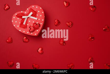 Red cardboard box with a gift on a red background, top view Stock Photo