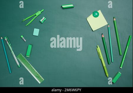 School supplies on empty green chalk board, top view. Back to school Stock Photo