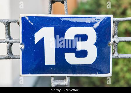 Weathered grunge square metal enameled plate of number of street address with number 13 Stock Photo