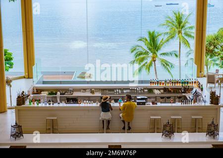 Couple drinking cocktails at a bar during vacation looking out over the ocean Stock Photo