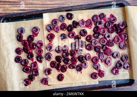 Roasted Cherries on a Parchment Paper-Lined Sheet Pan: Halved and pitted cherries roasted with a sprinkle of sugar viewed close-up Stock Photo