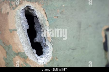 Hole or hole, armor deformation from a projectile close-up. Damaged armor of a Russian armored personnel carrier by shell fragme Stock Photo