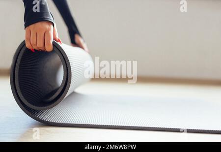 Side view of crop anonymous slim female  unrolling mat for yoga practice Stock Photo