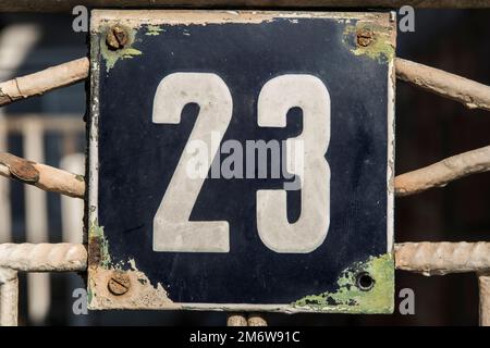 Weathered grunge square metal enameled plate of number of street address with number 23 Stock Photo