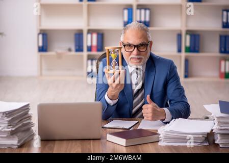 Old male employee in time management concept Stock Photo