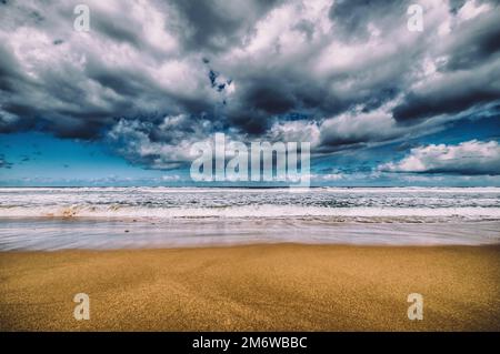 Deserted beach with ominous storm clouds out to sea Stock Photo