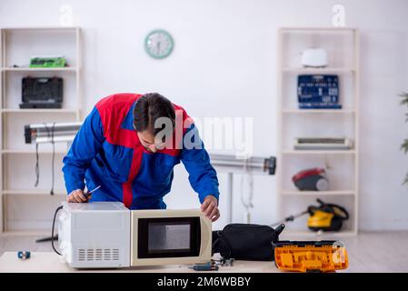 Young male repairman repairing oven at workshop Stock Photo