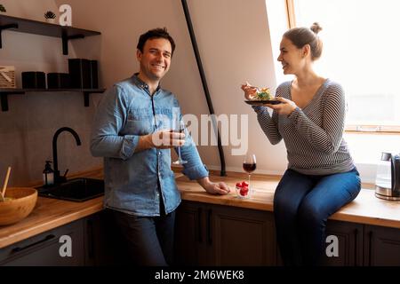 Side view of loving couple eating same spaghetti while having romantic dinner together at home Stock Photo