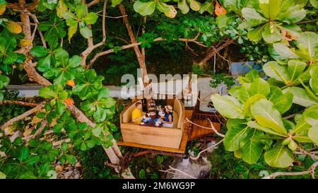 Couple having afternoon tea in a tree, men and women afternoon tea with snack in a basket in the tree Stock Photo