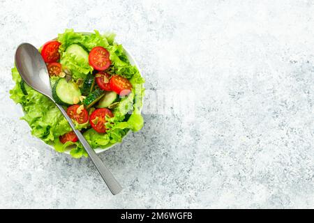 Healthy tomatoes cucumber iceberg leaves salad on white table top view Stock Photo