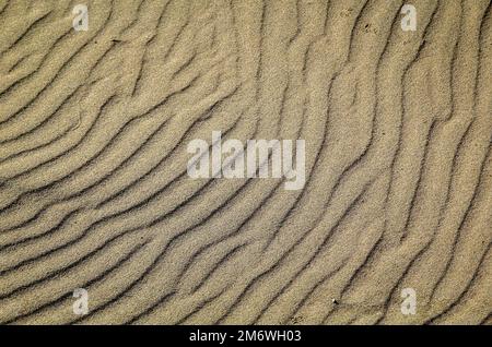 A texture of sand on the beach created by wind and waves. Stock Photo