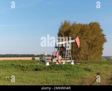 Operating oil and gas well in oil field, profiled against the blue sky Stock Photo