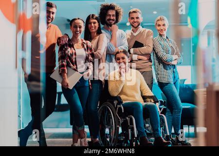 Businesswoman in a wheelchair on break in a modern office with her team in the background Stock Photo