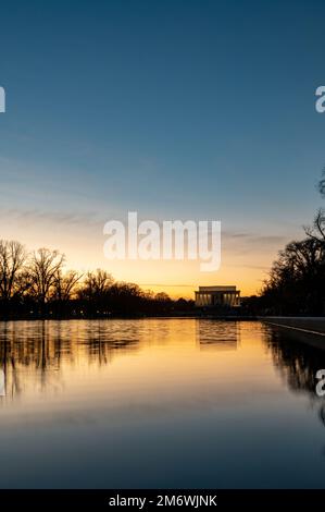 Sunset view with water reflection of the Lincoln Memorial, the monument located on the National Mall in Washington, D.C. NO clouds, dark mood. Stock Photo