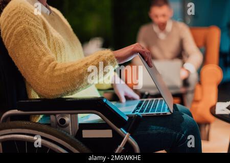 Businesswoman in wheelchair having business meeting with team at modern office. A group of young freelancers agree on new online Stock Photo