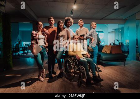 Businesswoman in a wheelchair on break in a modern office with her team in the background Stock Photo