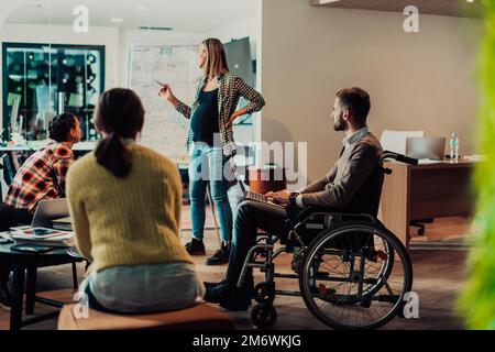 A pregnant businesswoman leads a creative meeting of a diverse business team in a modern coworking Stock Photo