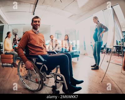 A pregnant businesswoman leads a creative meeting of a diverse business team in a modern coworking Stock Photo