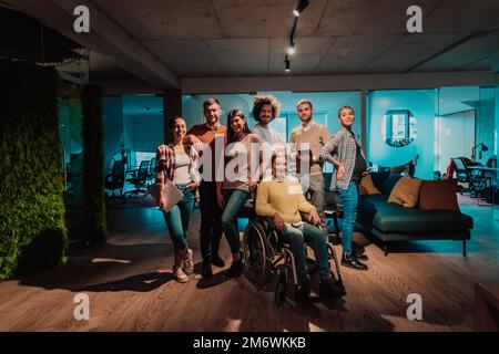 Businesswoman in a wheelchair on break in a modern office with her team in the background Stock Photo