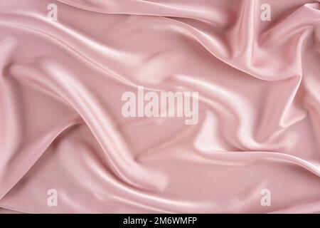 Pink silk background. Wavy folds pink silk texture satin material. Texture of the fabric. Pink cloth background. Place for text. Stock Photo