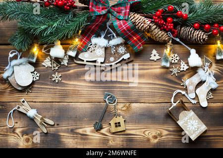 House key with keychain cottage on a festive eco friendly, natural background with Christmas tree. Happy New Year-red background Stock Photo