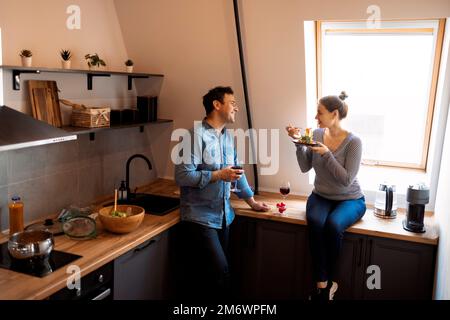 Side view of loving couple eating same spaghetti while having romantic dinner together at home Stock Photo